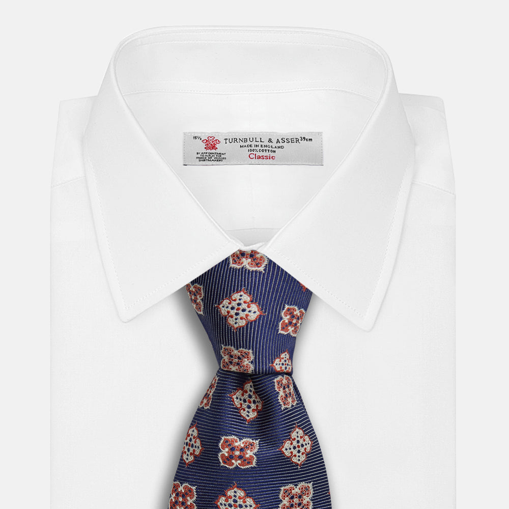 The Turnbull & Asser Burgundy Geometric Jacquard Tie features a bold, playful pattern of red and white dice scattered across its surface.