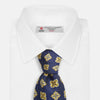 View 2 of product The Turnbull & Asser Yellow Geometric Jacquard Tie in navy features a repeating pattern of yellow geometric shapes with blue accents, presented rolled up on a white background.