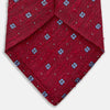 View 4 of product The Turnbull & Asser Red Square Silk Tie features a red and blue pattern with small white squares, elegantly rolled and displayed on a plain white background—a refined choice for men's accessories.