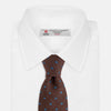 View 2 of product The Turnbull & Asser Brown Square Silk Tie, featuring a jacquard pattern of small blue squares and dots, is shown rolled up on a plain white background.