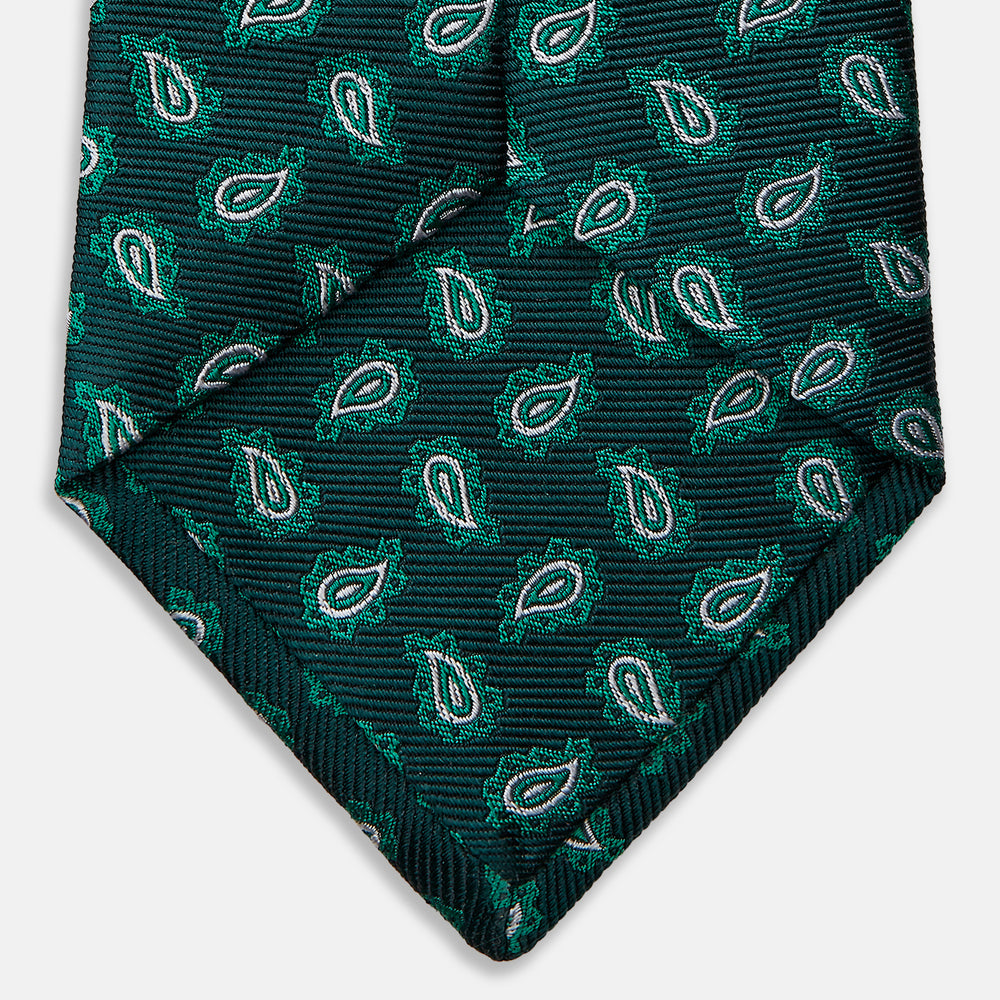 The Turnbull & Asser Green Abstract Paisley Silk Tie features a repeating light green paisley pattern on dark green silk, shown rolled up against a white background—a refined men’s accessory for making a statement.