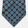 View 4 of product A rolled Navy Floral Geometric Tie by Turnbull & Asser, shown on a light background with light blue and white geometric floral motifs—a refined, stylish accessory.