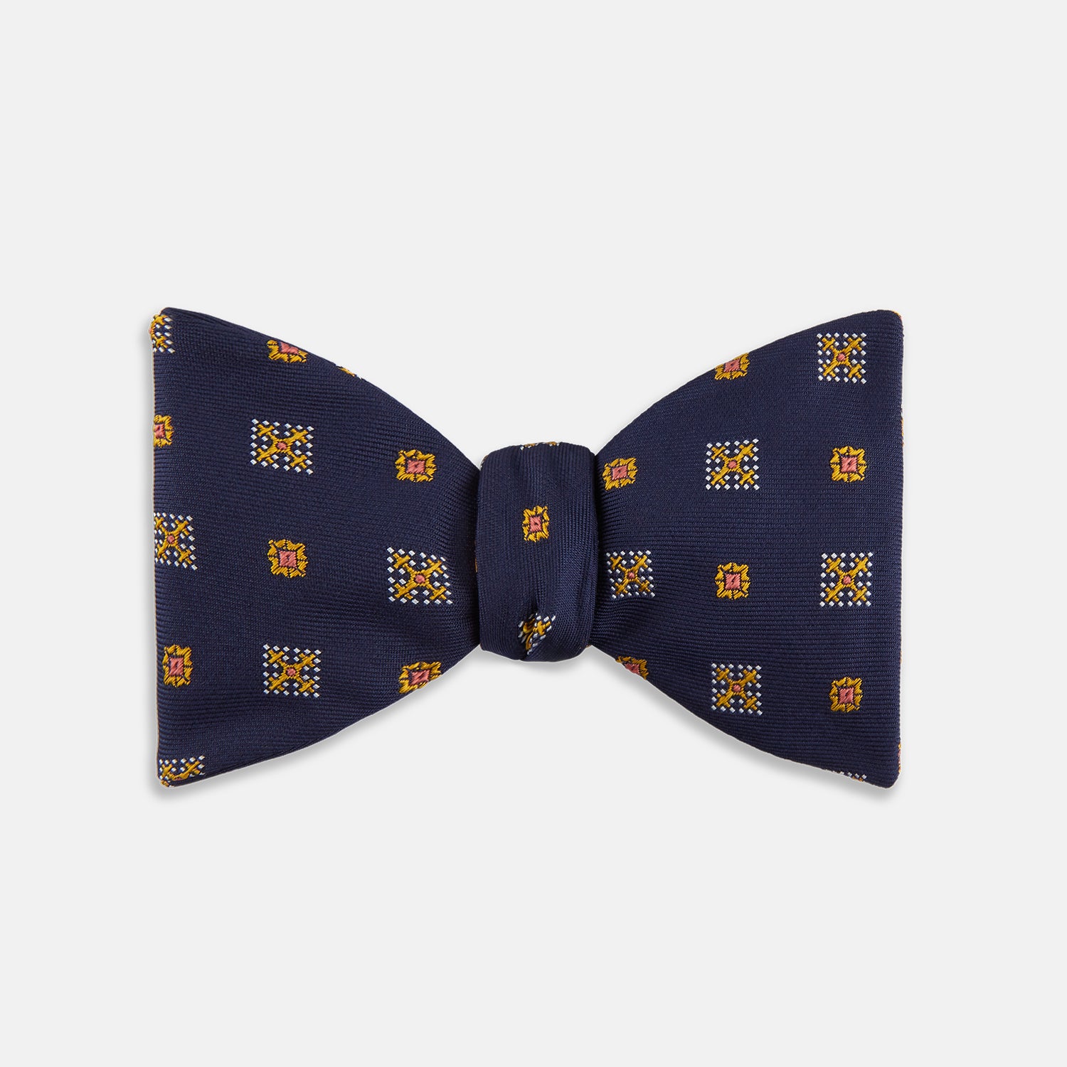View 1 of product The Yellow Shields Bow Tie by Turnbull & Asser features a navy blue base with small yellow, orange, and white geometric squares, ideal for formal occasions and shown against a white background.