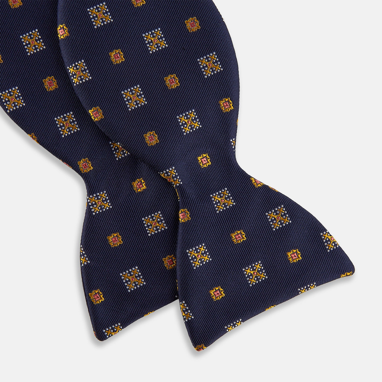 View 3 of product The Yellow Shields Bow Tie by Turnbull & Asser features a navy blue base with small yellow, orange, and white geometric squares, ideal for formal occasions and shown against a white background.