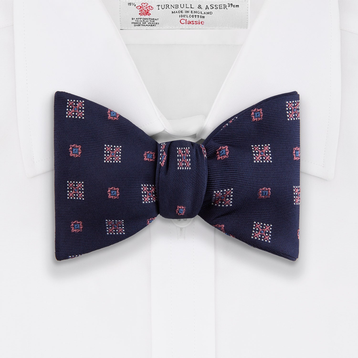 View 2 of product The Turnbull & Asser Pink Shields Bow Tie features a pink pattern with shield motifs, ideal for formal occasions and displayed on a plain white background.