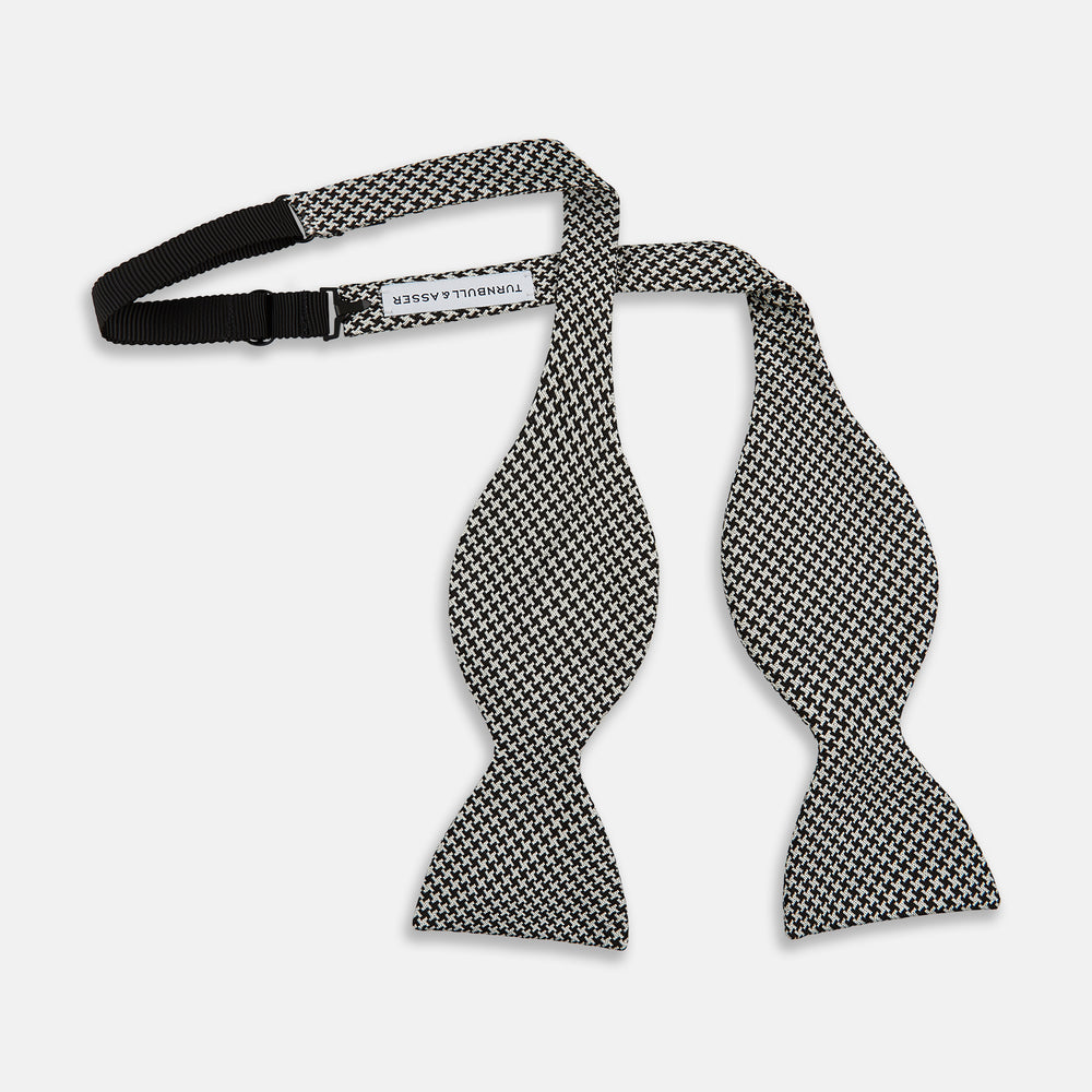The Turnbull & Asser Fine Puppytooth Monochrome Silk Bow Tie, shown on a white background, features a black and white puppytooth pattern—ideal for wearing with formalwear or an evening shirt.