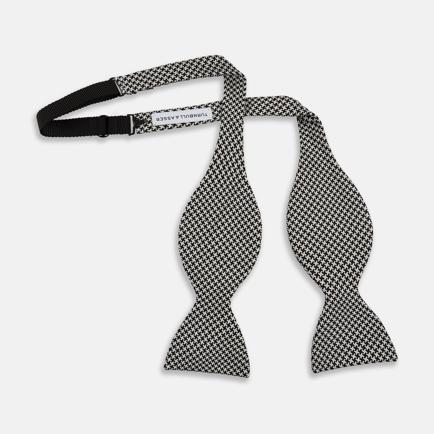View 3 of product The Turnbull & Asser Fine Puppytooth Monochrome Silk Bow Tie, shown on a white background, features a black and white puppytooth pattern—ideal for wearing with formalwear or an evening shirt.