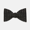 View 1 of product The Floral Piqué Monochrome Silk Bow Tie by Turnbull & Asser, featuring a repeating pattern of small white dots and hexagons on black silk, is ideal for formalwear or a dinner suit and is shown against a plain white background.