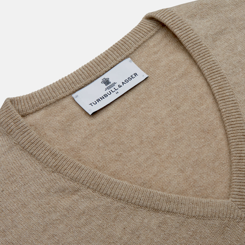 The Beige Paden V-Neck Jumper by Turnbull & Asser, made of pure cashmere, features long sleeves and ribbed cuffs and hem. It is shown flat on a white background with the label visible at the neckline.