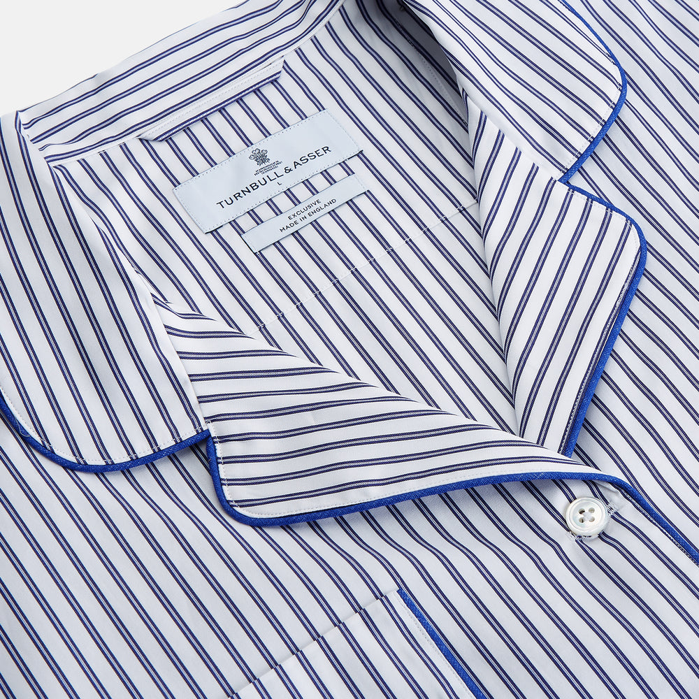The Women's Dara Navy Stripe Pyjama Set by Turnbull & Asser features a long-sleeve button-up shirt with chest pocket and drawstring pants in premium cotton, shown neatly on a white background.
