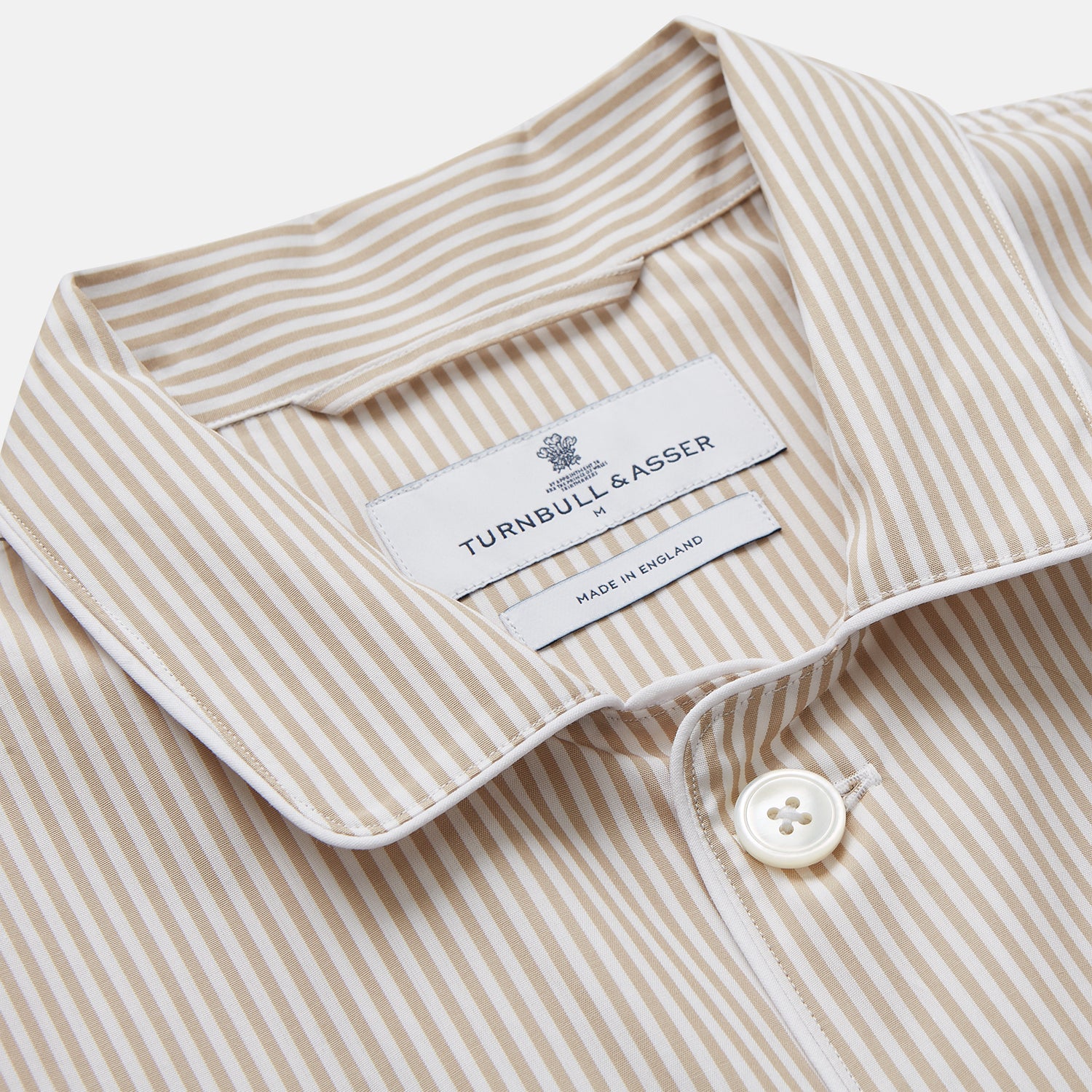 View 2 of product The Turnbull & Asser Sand Bengal Stripe Modern Fit Cotton Pyjama Set features cream-colored striped Italian cotton, with a long-sleeved button-up top and matching drawstring pants, neatly displayed against a white background.