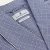 View 2 of product The Turnbull & Asser Navy Check Cotton Gown features long sleeves, white piping, a shawl collar, chest pocket, and matching waist belt, all in a blue plaid pattern. Shown against a plain white background.
