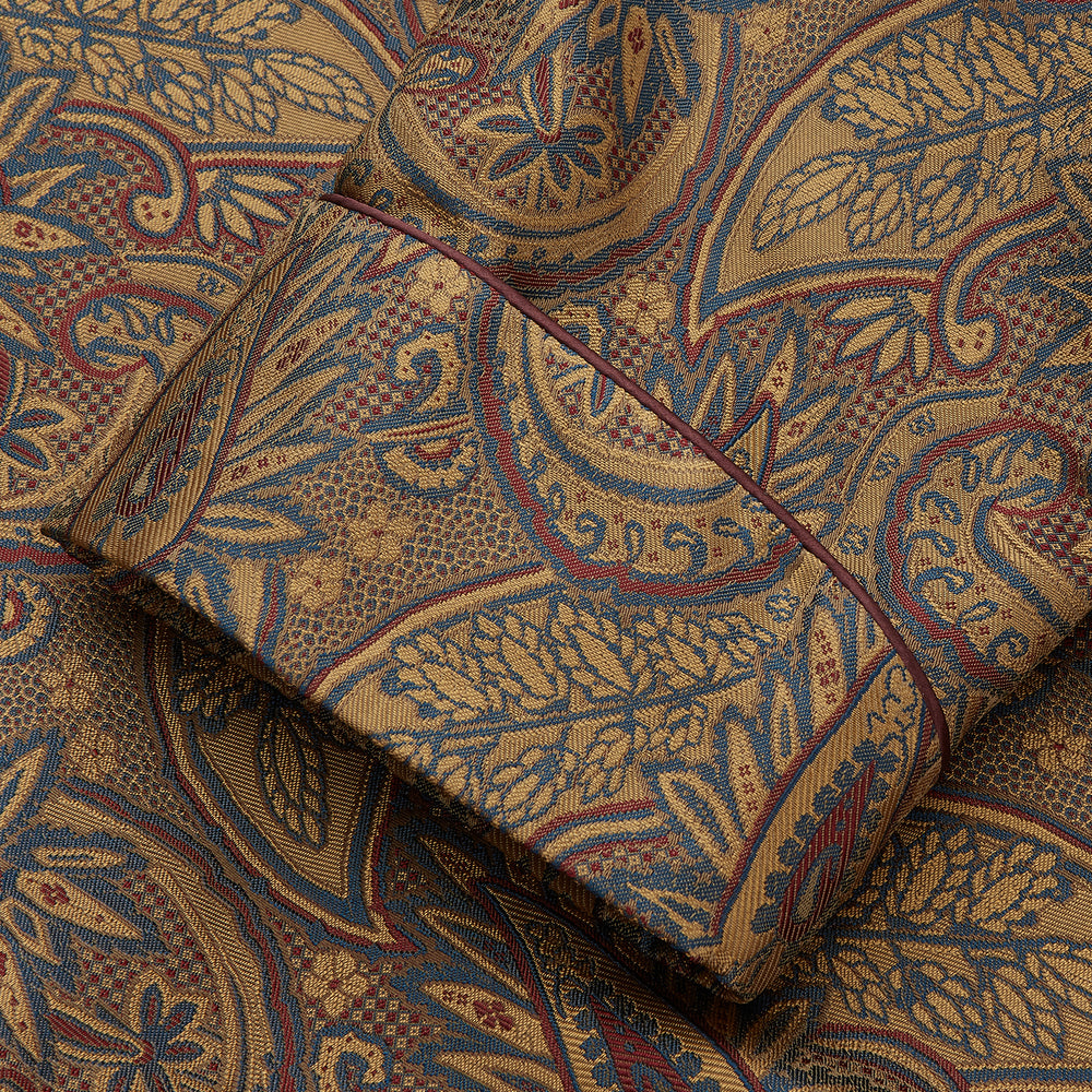 The Turnbull & Asser Gold Paisley Traditional Silk Jacquard Gown features a brown and gold paisley pattern, shawl collar, front pockets, and matching fabric belt. Displayed on a white background, it’s perfect for winter comfort.