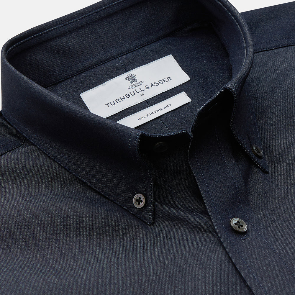 The Turnbull & Asser Navy Chambray Weekend Fit Shirt features a Dorset collar, long sleeves with 1-button cuffs, and two button-flap chest pockets. This officer’s shirt is displayed flat on a white background.