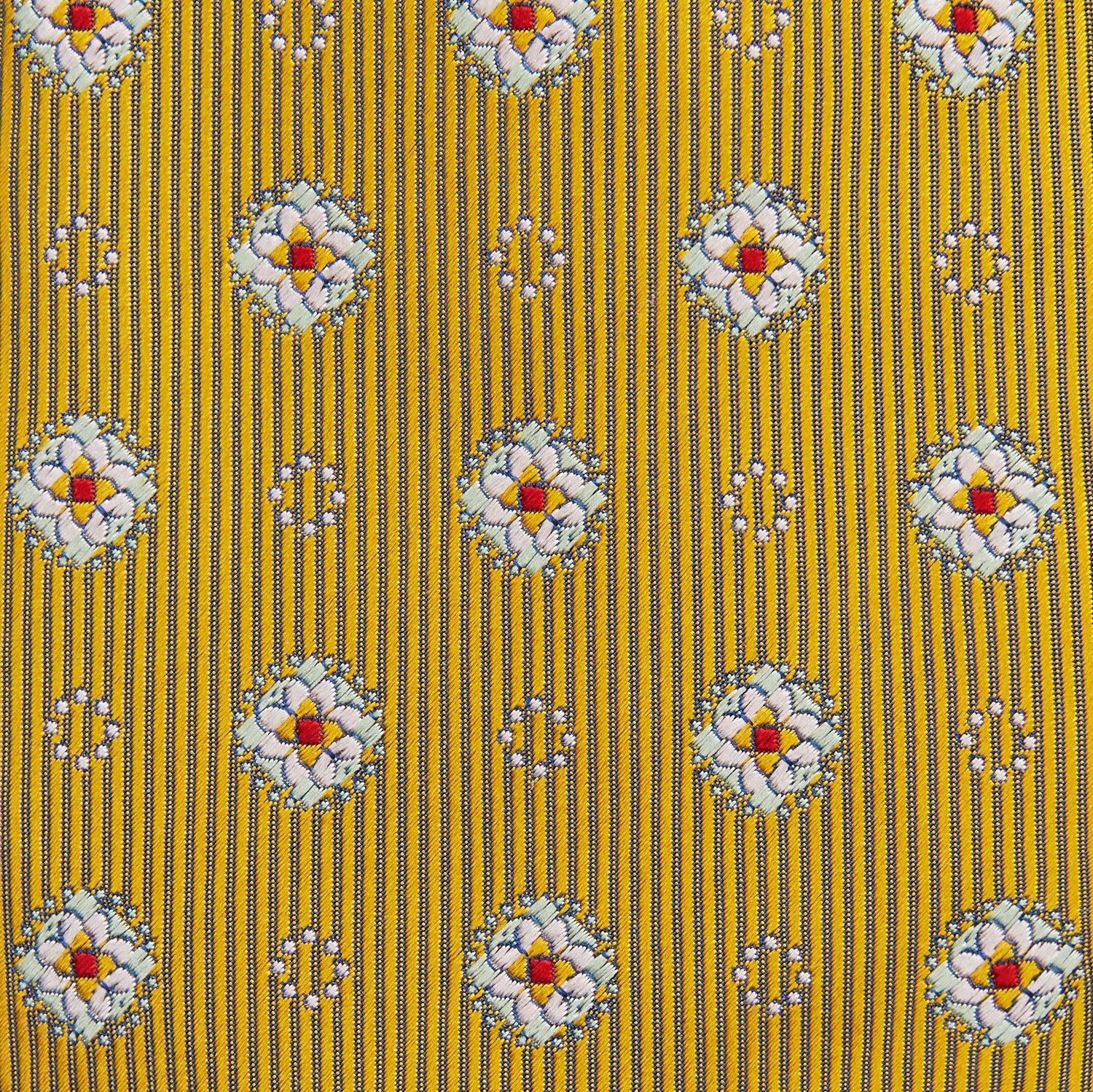 View 3 of product The Yellow Multi Floral Motif Silk Tie by Turnbull & Asser features subtle diagonal stripes and small white, blue, and orange floral motifs—a perfect summer palette, shown rolled up on a plain white background.