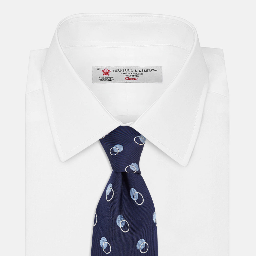 The Turnbull & Asser Navy Multi Circle Silk Tie showcases overlapping light blue and white rings on navy silk—a stylish choice to elevate bold shirts or bring visual interest to your summer look.