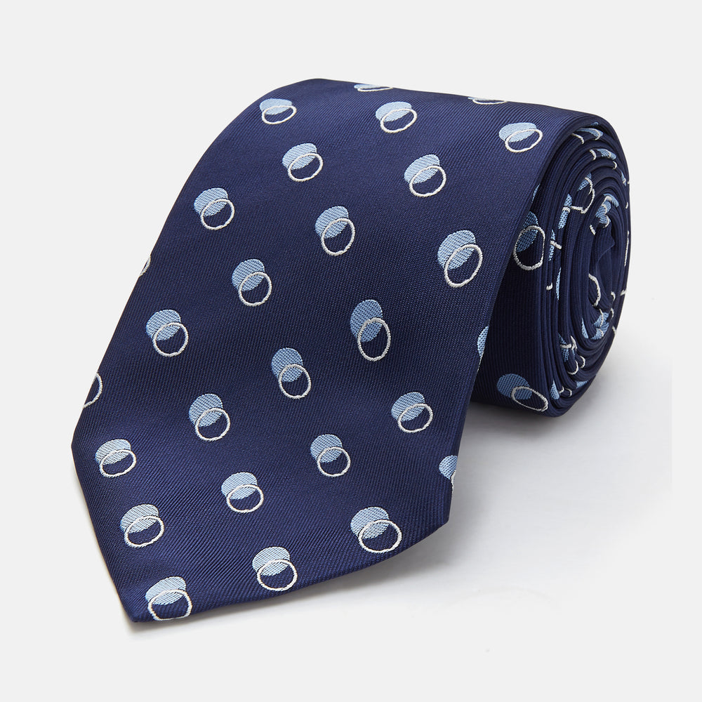 The Turnbull & Asser Navy Multi Circle Silk Tie showcases overlapping light blue and white rings on navy silk—a stylish choice to elevate bold shirts or bring visual interest to your summer look.