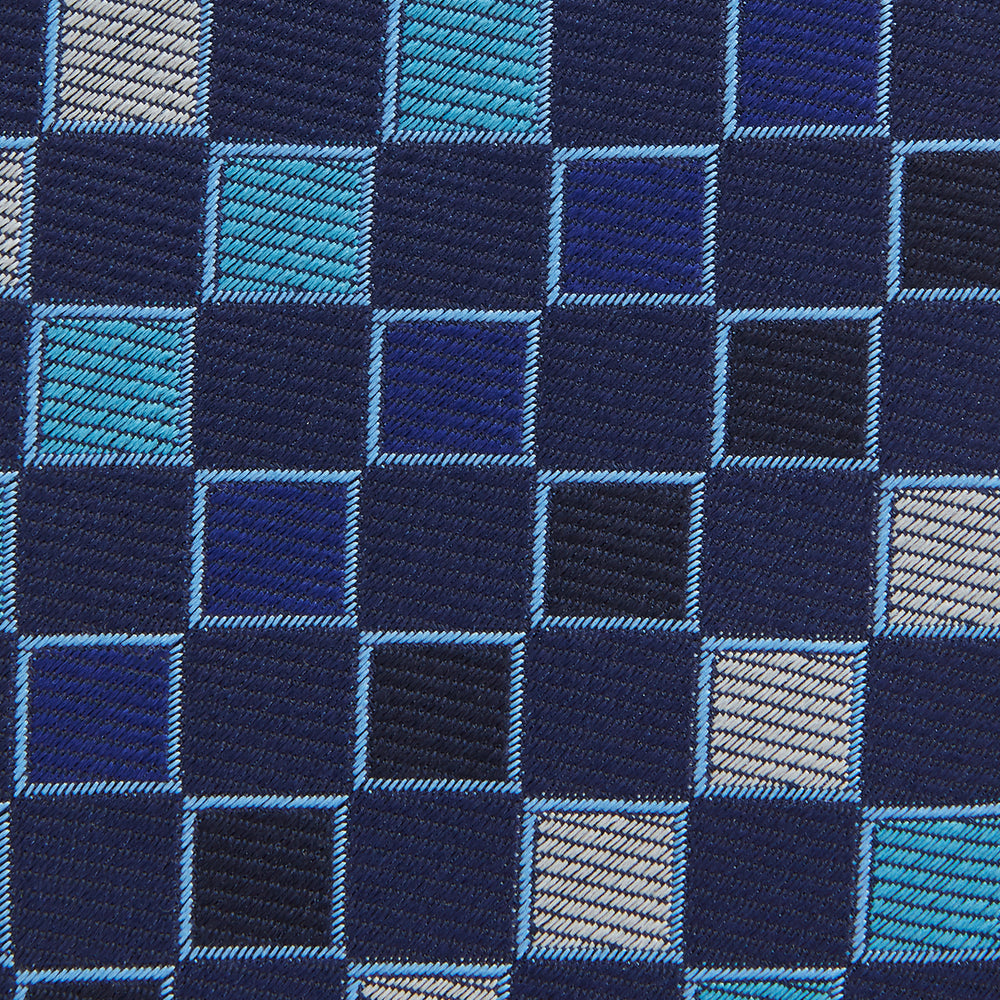 The Blue Multi Check Silk Tie by Turnbull & Asser features a geometric checked pattern in blue, light blue, and silver on dark navy—ideal for pairing with bold shirts.