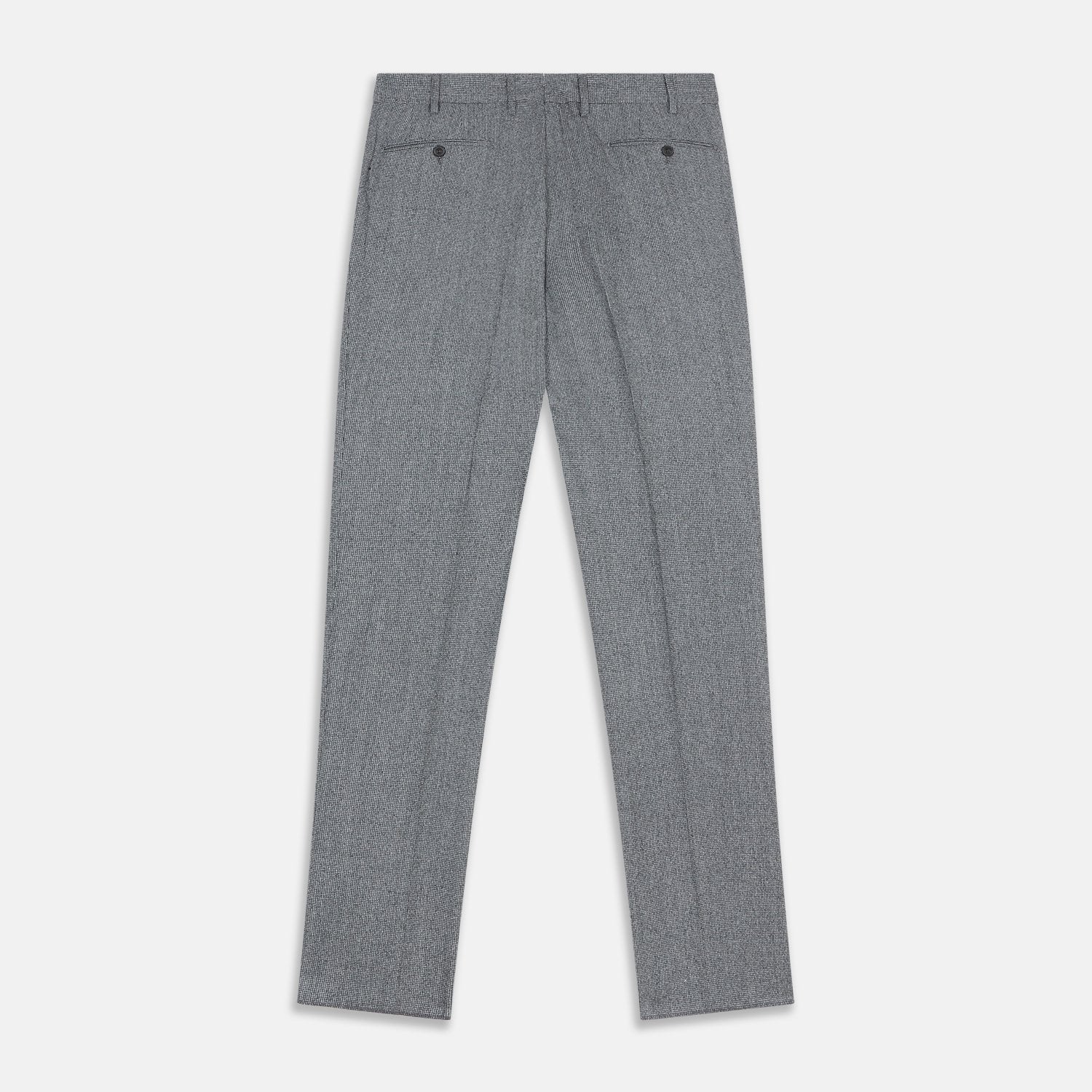 View 7 of product A person wears Turnbull & Asser Grey Puppytooth Wool Manson Trousers, a white dress shirt with rolled-up sleeves, and black shoes, standing against a plain beige background.
