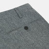 View 3 of product A person wears Turnbull & Asser Grey Puppytooth Wool Manson Trousers, a white dress shirt with rolled-up sleeves, and black shoes, standing against a plain beige background.