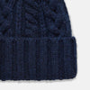 View 2 of product The Turnbull & Asser Navy Cashmere Cable Hat features a ribbed fold-over cuff and cable knit pattern, shown on a plain light background.