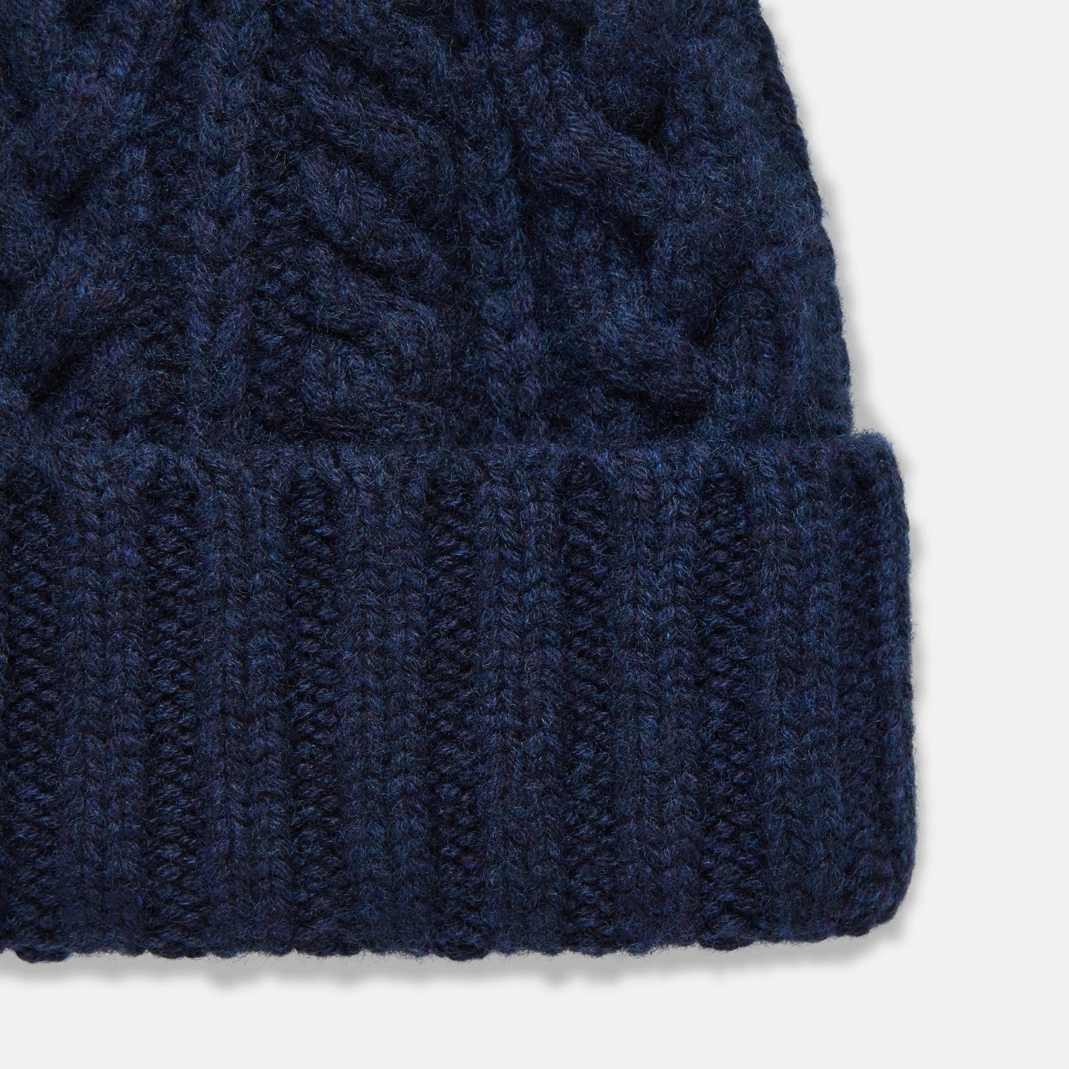 View 2 of product The Turnbull & Asser Navy Cashmere Cable Hat features a ribbed fold-over cuff and cable knit pattern, shown on a plain light background.