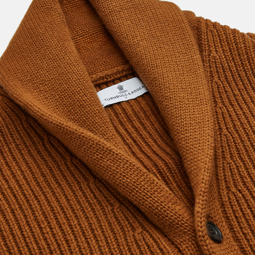The Brown Ainsley Ribbed Shawl Cashmere Cardigan by Turnbull & Asser features a ribbed knit texture, black front buttons, and two front pockets, displayed laid flat on a white background.