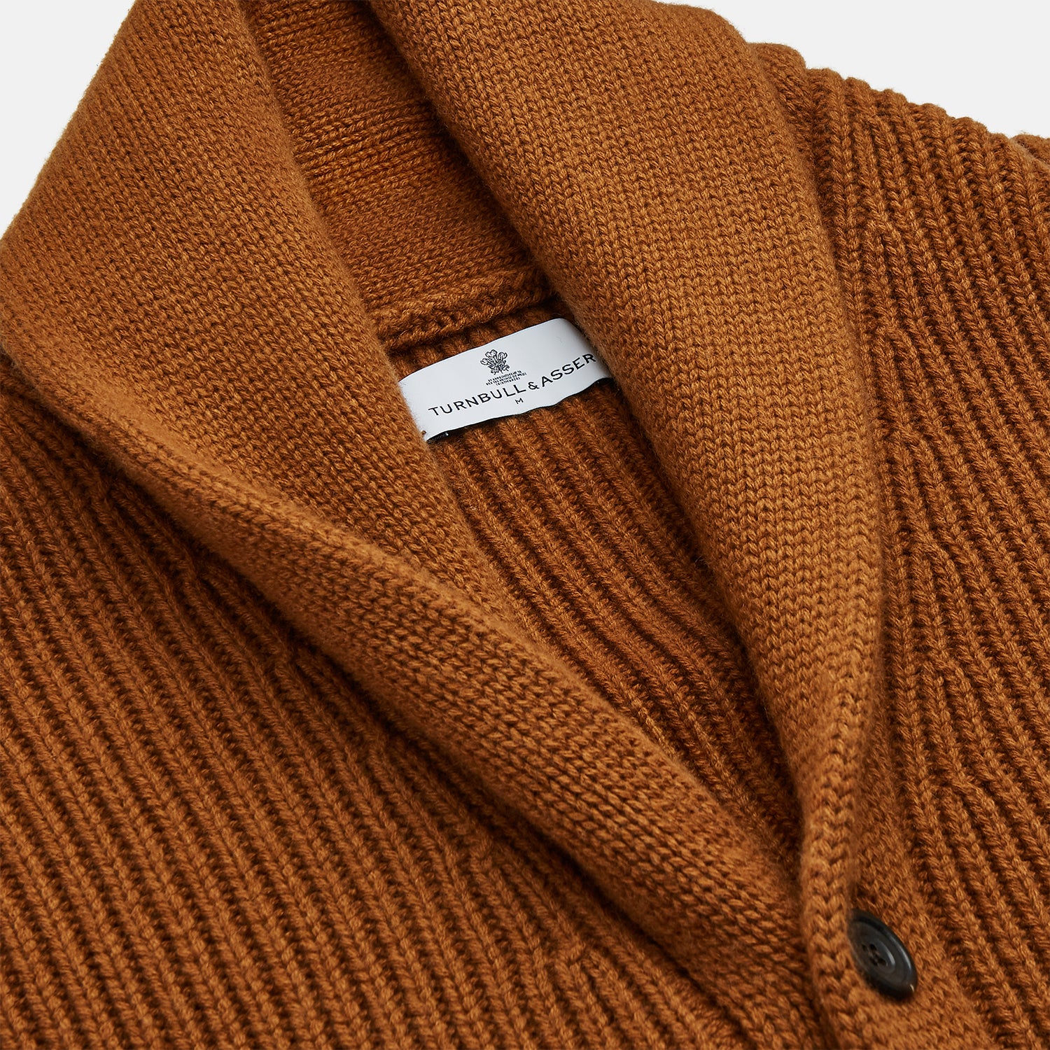 View 3 of product The Brown Ainsley Ribbed Shawl Cashmere Cardigan by Turnbull & Asser features a ribbed knit texture, black front buttons, and two front pockets, displayed laid flat on a white background.