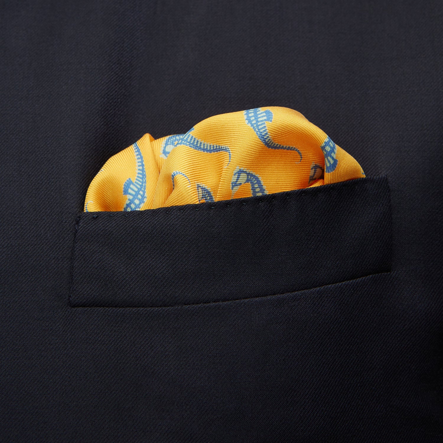 View 3 of product The Turnbull & Asser Yellow & Blue Seahorse Silk Pocket Square features a repeating seahorse pattern in diagonal rows and is handprinted in England, with branding in two corners.
