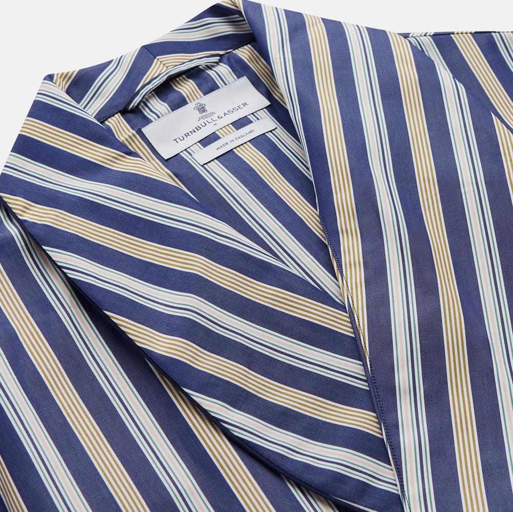 The Turnbull & Asser Blue Multi Stripe Cotton Gown features blue and white vertical stripes, long sleeves, a shawl collar, front pockets, and a matching waist tie, shown on a plain white background.