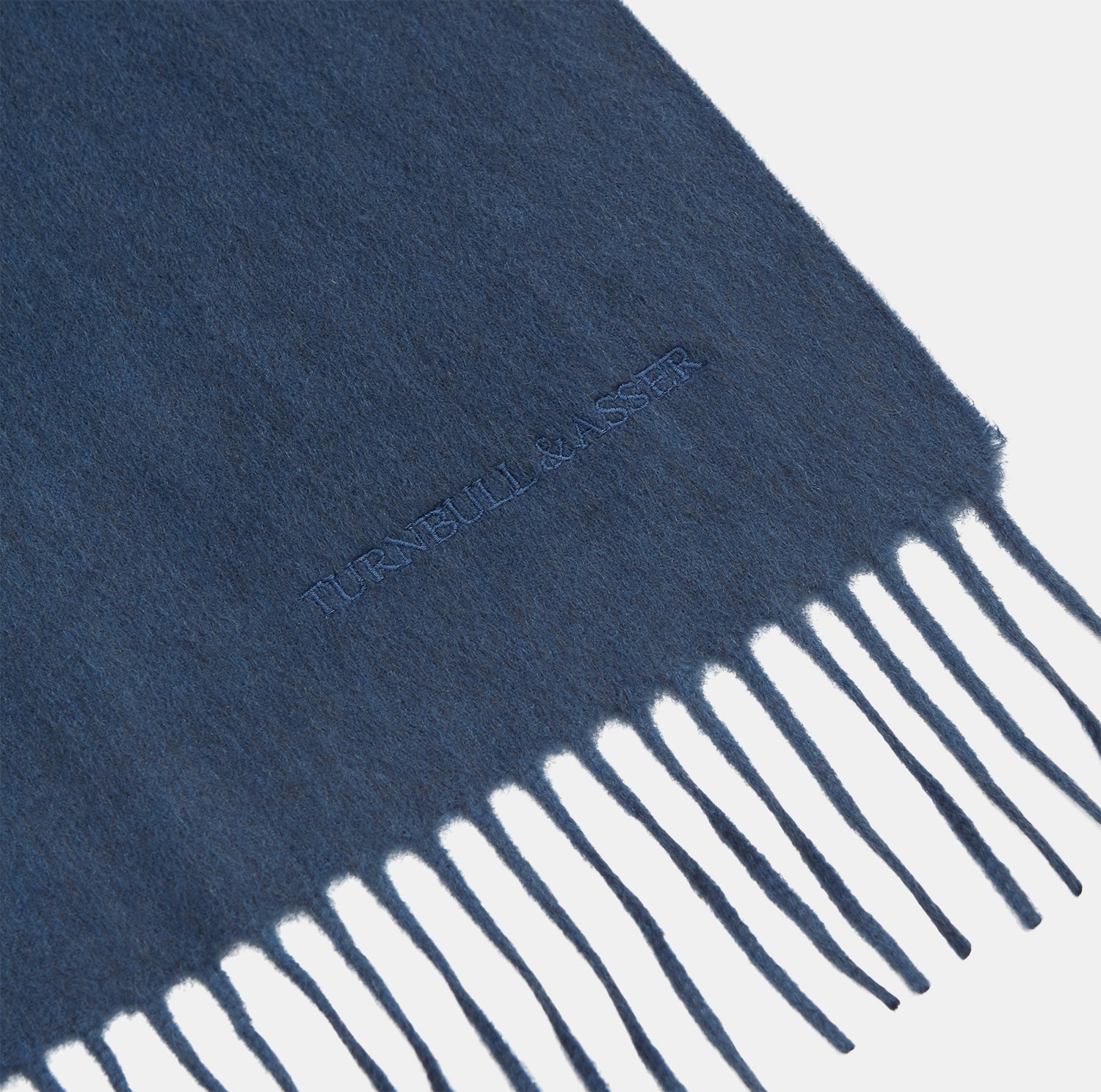 View 2 of product The Turnbull & Asser Slate Blue Purled Fringe Cashmere Scarf, neatly folded on a white background, is a stylish winter accessory.