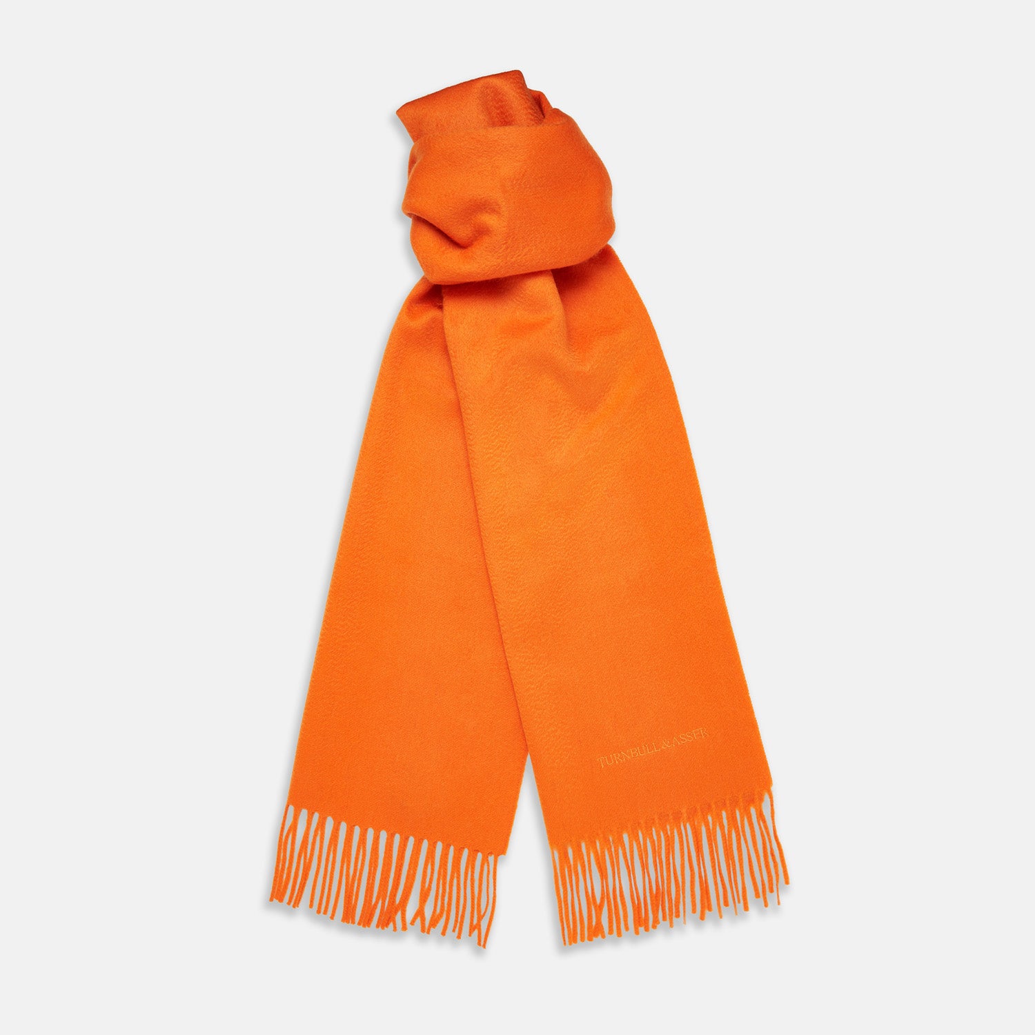 View 1 of product The Turnbull & Asser Orange Purled Fringe Cashmere Scarf is shown neatly arranged on a white background, featuring soft, thick cashmere with fringe at both ends and a subtle embroidered logo near one edge.