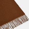 View 2 of product The Turnbull & Asser Rust Cashmere Wilde Stole Scarf is oversized with a soft texture, features short fringe detailing on the ends, and is shown loosely tied against a plain white background.