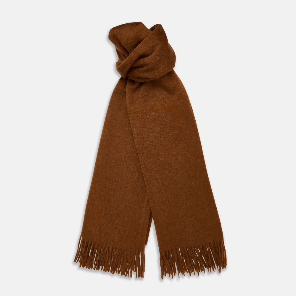 The Turnbull & Asser Rust Cashmere Wilde Stole Scarf is oversized with a soft texture, features short fringe detailing on the ends, and is shown loosely tied against a plain white background.