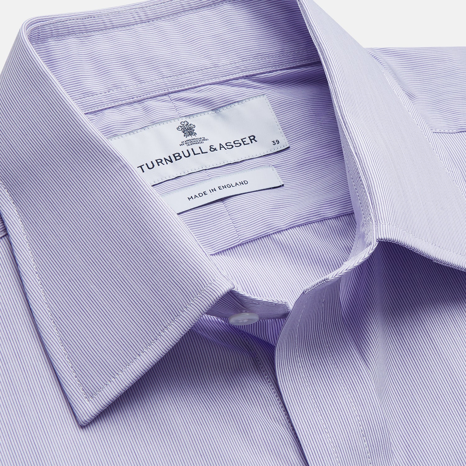 View 2 of product The Turnbull & Asser Purple Hairline Stripe Regular Fit Twill Shirt features a T&A collar, double cuffs, long sleeves, and white buttons, shown laid flat on a white background.