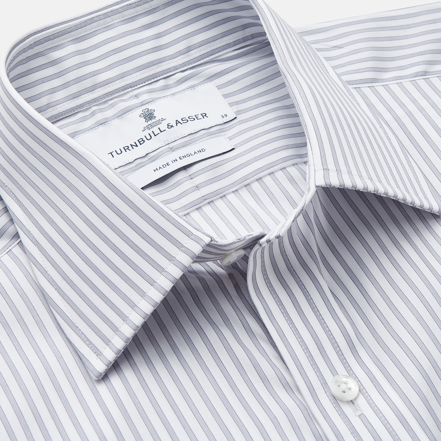 View 3 of product A man wearing the Turnbull & Asser Grey Multi Stripe Regular Fit Twill Shirt with T&A Collar and Double Cuffs stands against a beige background, one hand in his pocket, looking at the camera.