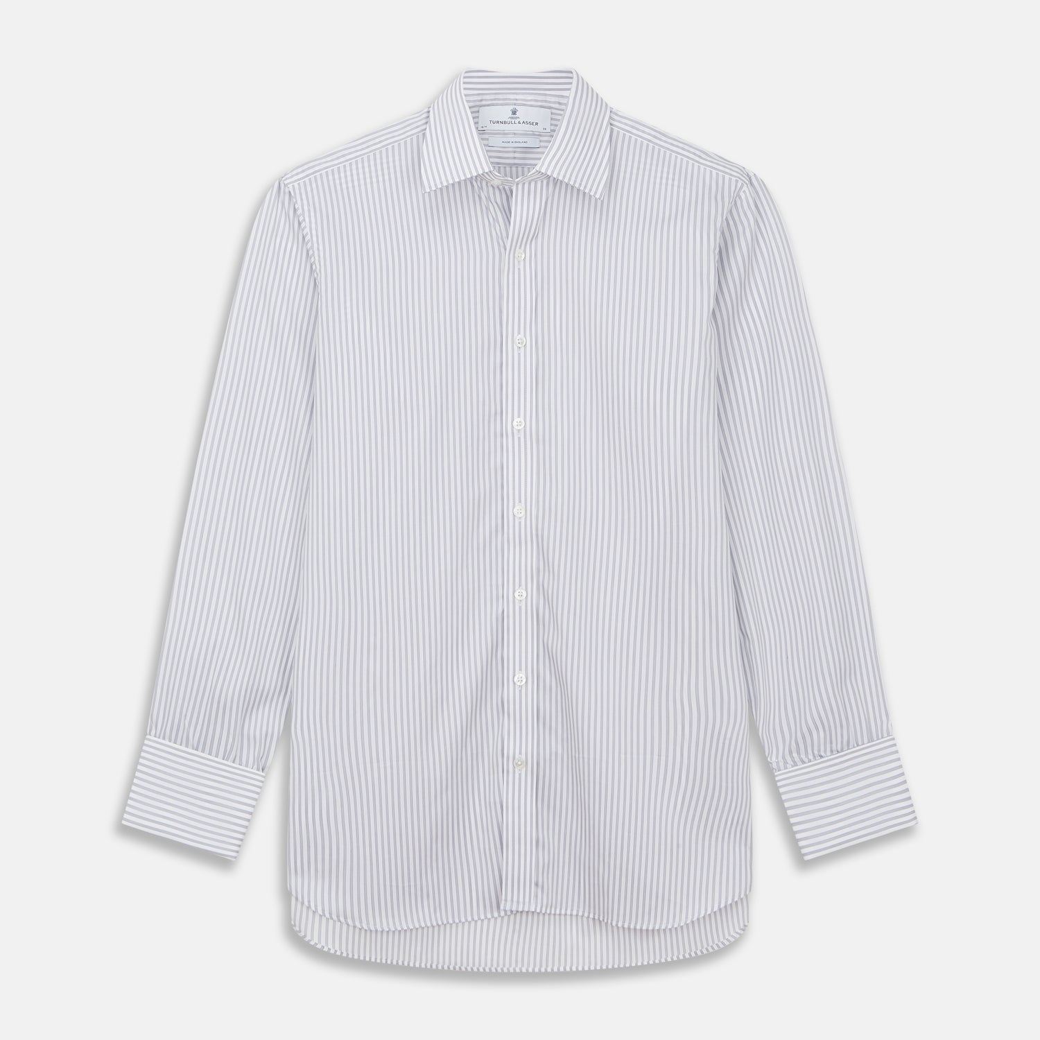 View 2 of product A man wearing the Turnbull & Asser Grey Multi Stripe Regular Fit Twill Shirt with T&A Collar and Double Cuffs stands against a beige background, one hand in his pocket, looking at the camera.