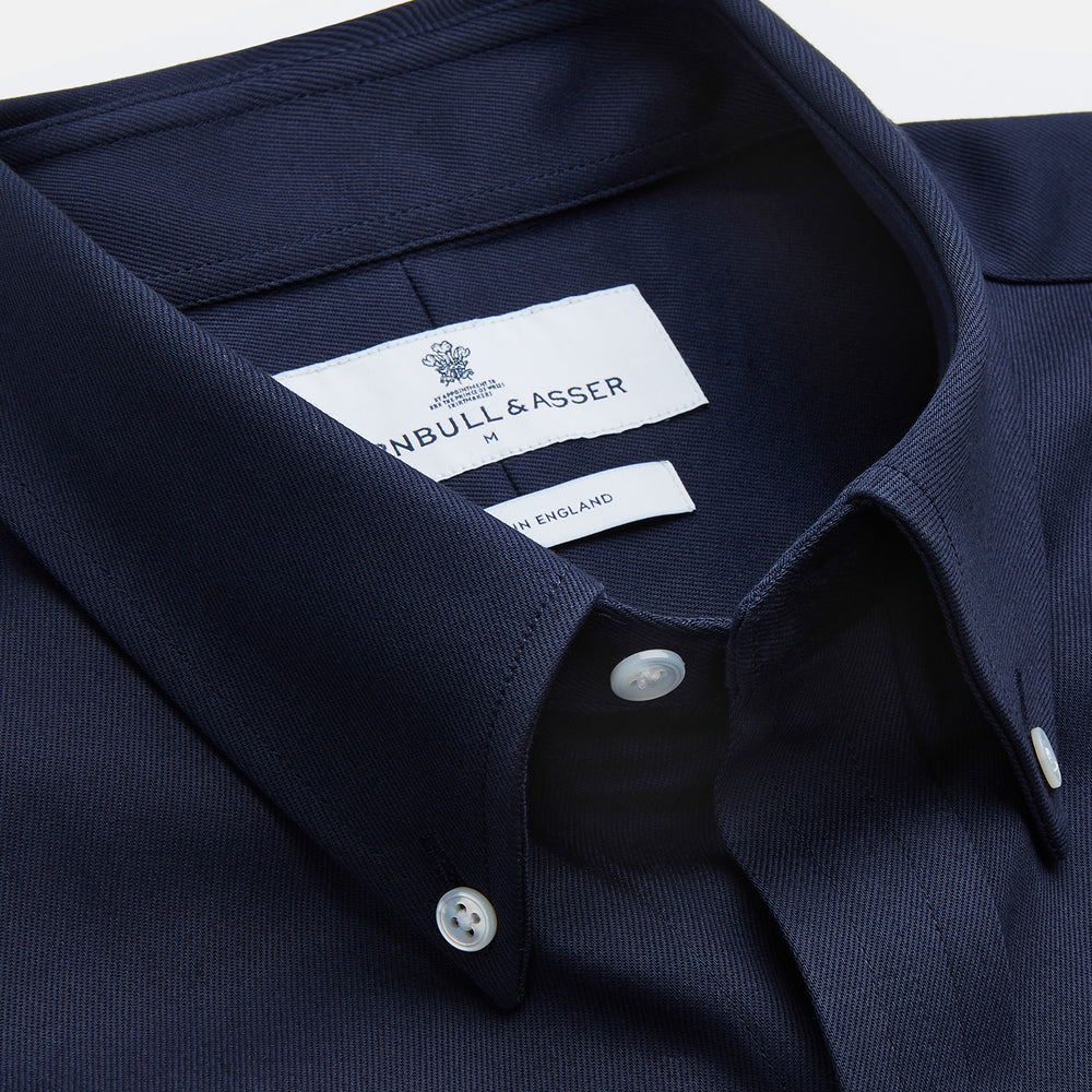 The Turnbull & Asser Navy Weekend Fit Shirt features a Dorset collar, 1 button cuffs, and white buttons, shown laid flat against a white background.
