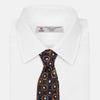 View 2 of product The Turnbull & Asser Orange Multi Circle Printed Silk Tie features navy blue silk with orange circles and white ovals, perfect for elevating any formal outfit. Shown on a plain white background.