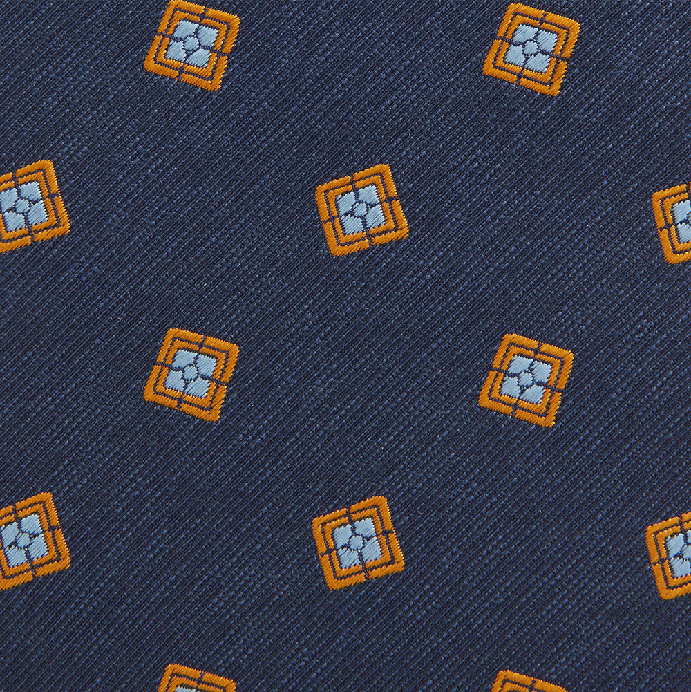 The Turnbull & Asser Orange Multi Geo Silk Tie, featuring a vibrant geometric pattern, is showcased rolled up on a plain white background—an elegant piece from our autumn-winter collection.