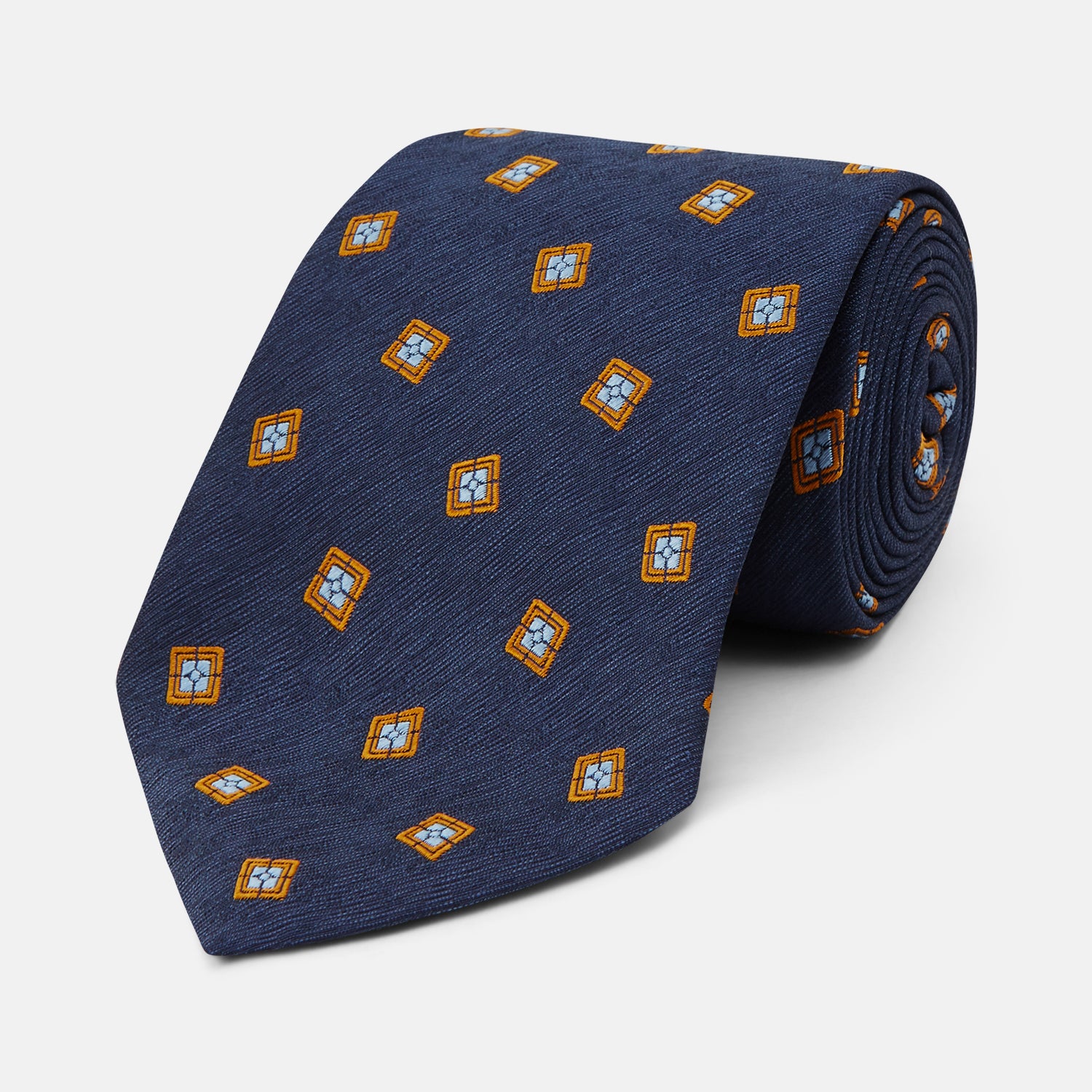 View 1 of product The Turnbull & Asser Orange Multi Geo Silk Tie, featuring a vibrant geometric pattern, is showcased rolled up on a plain white background—an elegant piece from our autumn-winter collection.