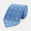 View 1 of product The Blue Multi Neat Silk Tie by Turnbull & Asser features a geometric pattern of white four-pointed shapes and circles, crafted in blue silk from the autumn-winter collection. Displayed rolled on a plain light background.