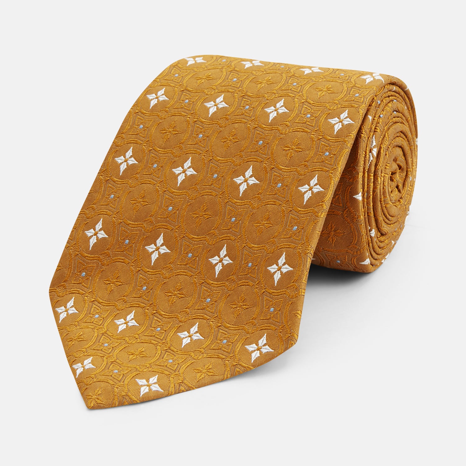 View 1 of product The Orange Multi Neat Silk Tie by Turnbull & Asser, from the autumn-winter collection, features a golden yellow geometric pattern on textured silk. Shown rolled on a white background, it pairs perfectly with bold signature shirts.