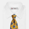 View 2 of product A rolled-up Turnbull & Asser Gold Shadow Spot Printed Silk Tie, featuring blue and white circular patterns on fine Adamley Macclesfield silk, displayed against a white background.