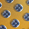 View 3 of product A rolled-up Turnbull & Asser Gold Shadow Spot Printed Silk Tie, featuring blue and white circular patterns on fine Adamley Macclesfield silk, displayed against a white background.