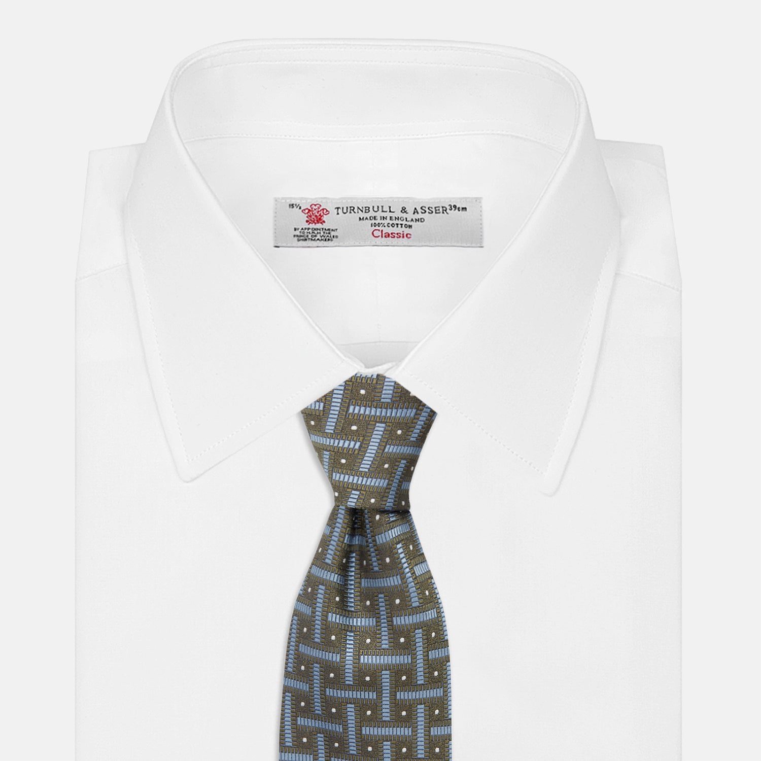 View 2 of product The Turnbull & Asser Green & Navy Cross Silk Tie features an olive green base with navy geometric patterns and white dots, shown rolled on a light surface—an ideal accessory to elevate any formal look.