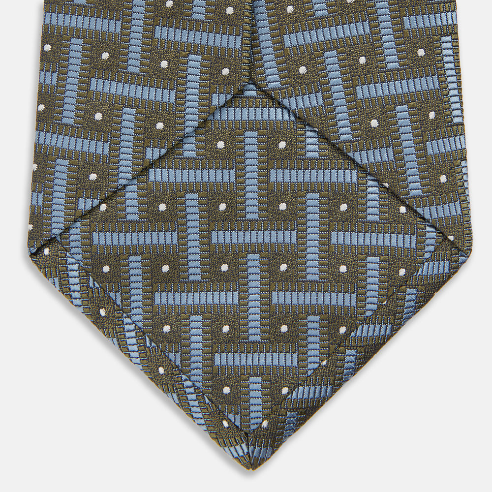 The Turnbull & Asser Green & Navy Cross Silk Tie features an olive green base with navy geometric patterns and white dots, shown rolled on a light surface—an ideal accessory to elevate any formal look.