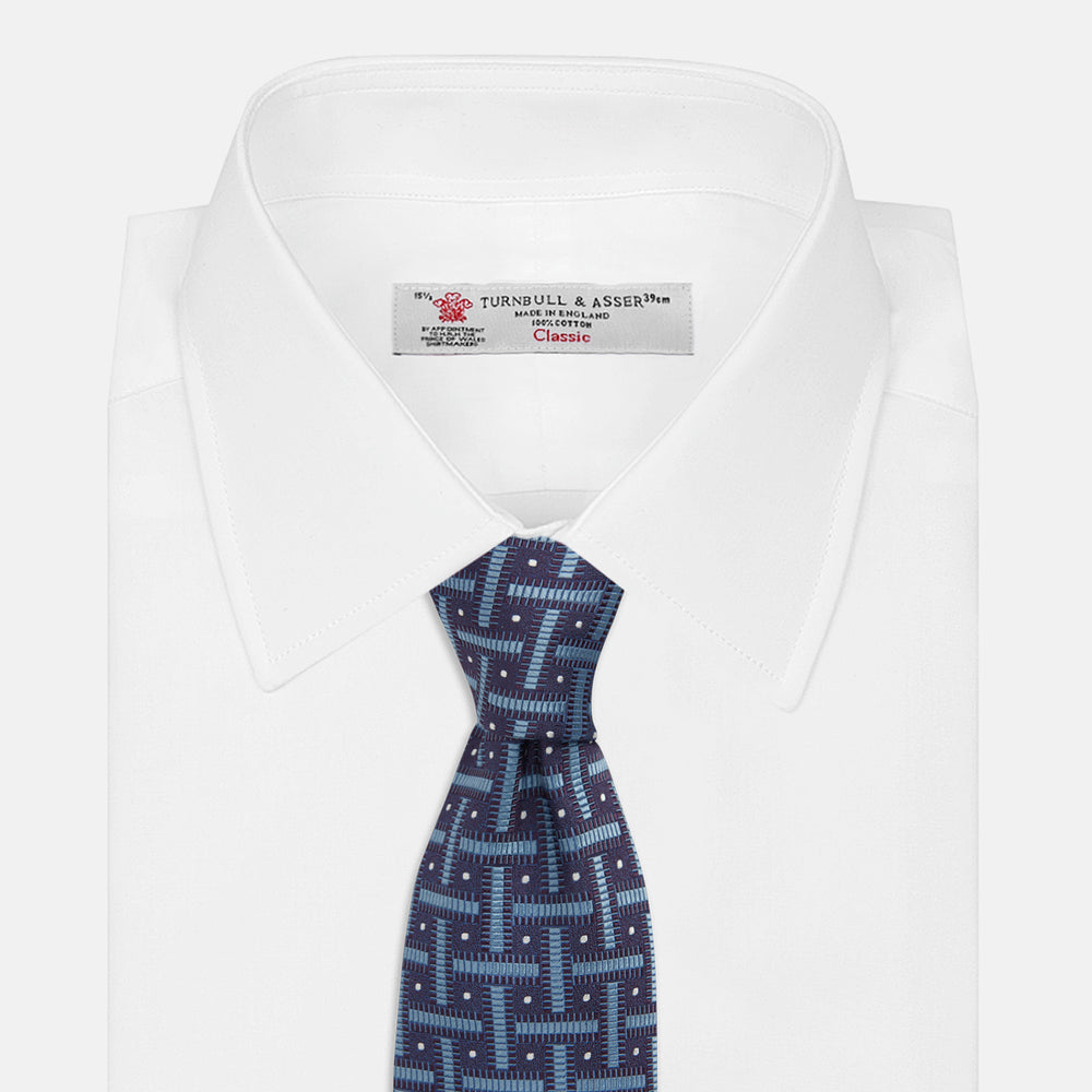 The Turnbull & Asser Navy & Blue Cross Silk Tie features a navy silk base with light blue and white geometric patterns and small white dots—ideal for elevating formal looks or pairing with signature shirts.