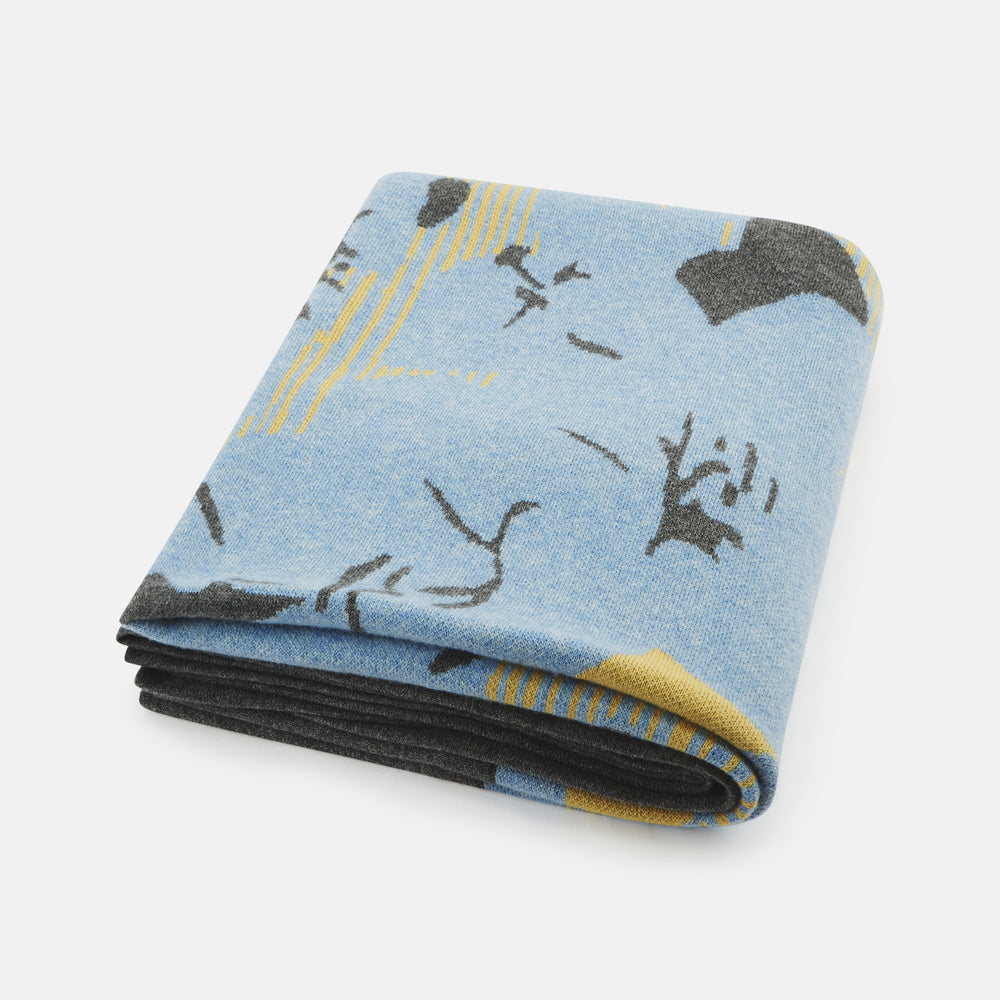 The Pale Blue Wool and Cashmere Lily Blanket by Turnbull & Asser features abstract, hand-drawn designs in blue, yellow, and gray on a white background.