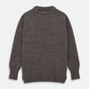 View 1 of product The Turnbull & Asser Fallow Wool and Cotton Blend Lewis Guernsey Jumper is a plain, long-sleeved dark gray knit with ribbed crew neck, cuffs, and hem, shown laid flat on a white background.
